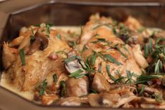 a close up of food in a pan with mushrooms and herbs on the top of it