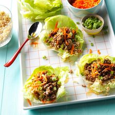 lettuce wraps with meat, carrots and other vegetables on a white tray