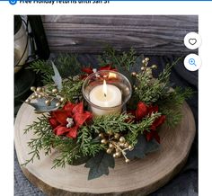 a candle that is sitting on top of a tree stump with greenery and poinsettis