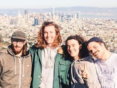 three men standing next to each other in front of a city