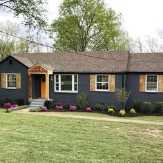 a blue house with yellow shutters and flowers in the front yard