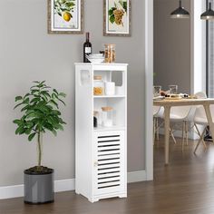 a small white cabinet next to a potted plant