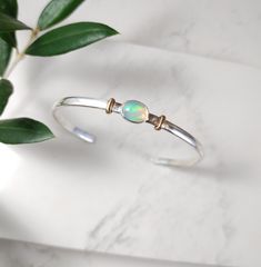 Stunning oval Opal gemstone placed in a sterling silver bezel setting and set on a sterling silver cuff bracelet with 14k gold filled design.  This bracelet makes a great gift for someone special or yourself. This Opal mixed metal cuff bracelet matches our mized metal opal ring. D E T A I L S. . . . . . .  Metal: Sterling Silver and 14k Gold Filled Gemstone: Opal Size: Available in Small, Medium, or Large Handmade jewelry with Love and Passion by Grace Lilly Designs. Handcrafted in the USA. Sterling Silver Oval Gemstone Cuff Bracelet, Oval Sterling Silver Gemstone Cuff Bracelet, Adjustable Oval Sterling Silver Cuff Bracelet, Silver Sterling Silver Cuff Bracelet With Cabochon, Silver Cabochon Cuff Bracelet Gift, Adjustable Sterling Silver Cuff Bracelet With Gemstone, Adjustable Sterling Silver Cuff Bracelet With Cabochon, Adjustable Sterling Silver Cabochon Cuff Bracelet, Adjustable Cabochon Sterling Silver Cuff Bracelet