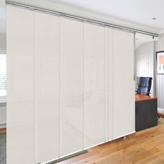 an empty room with a desk and chair in front of the sliding glass doors that are open