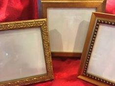 three gold frames sitting on top of a red cloth covered floor next to each other