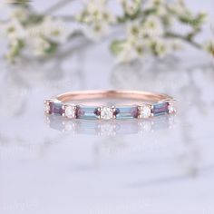 an image of a wedding ring with three stones on the side and flowers in the background