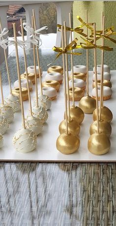 there are many desserts on the table with gold and white candy sticks in them