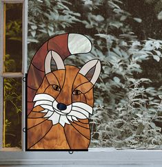 a stained glass window with a red fox on it's face in front of trees