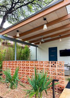 an outdoor living area with a wooden fence and potted plants on the side of the house