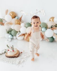 a baby standing in front of a cake