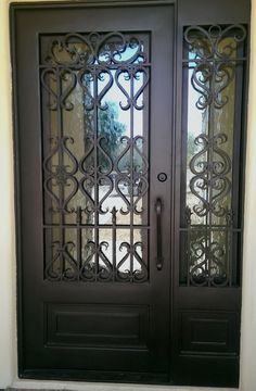 an iron door with two sidelights and glass panels on the front entrance to a home