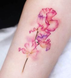 a watercolor tattoo with pink flowers on the arm