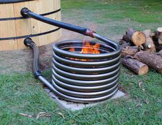 a hose is connected to a fire in the middle of some logs and grass near a barrel