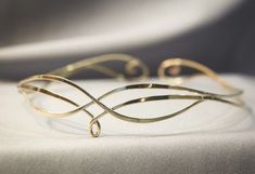 a close up of a gold bracelet on a white cloth with an object in the background