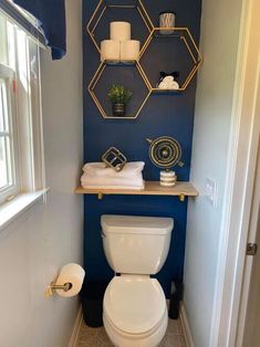 a white toilet sitting in a bathroom next to a shelf filled with rolls of toilet paper