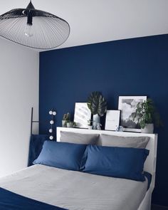 a bedroom with blue walls and white bedding