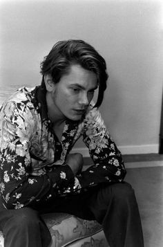 black and white photograph of a man sitting on the floor with his hands under his face