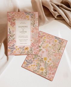 two cards with flowers on them sitting next to each other, one in pink and the other in gold