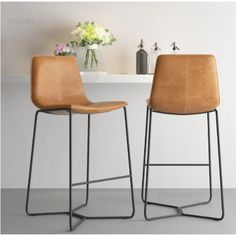 two brown chairs sitting next to each other in front of a white table with flowers on it