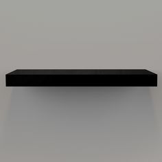 a black shelf is shown against a gray wall with light coming from the top and bottom