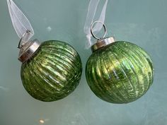 two green glass ornaments hanging on a wall