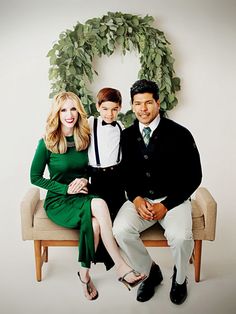 a man, woman and child sitting on a bench in front of a wreath