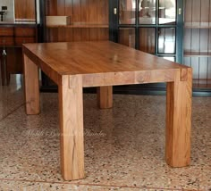 a wooden table sitting on top of a tiled floor next to cabinets and cupboards