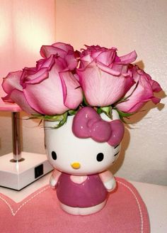 a hello kitty vase with pink roses in it