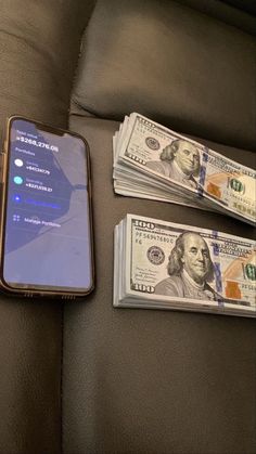 a cell phone sitting on top of a couch next to stacks of $ 100 bills