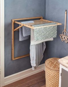 an ironing board hanging on the wall next to a clothes rack and laundry basket