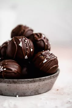 a bowl filled with chocolate covered donuts on top of a table