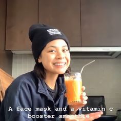 a woman is holding a glass with orange juice in it and smiling at the camera