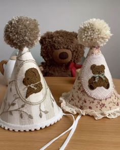 two teddy bears sitting next to each other on top of a wooden table and wearing hats