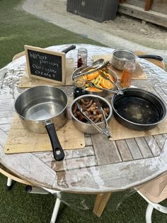 a table topped with pots and pans filled with food next to a chalkboard sign