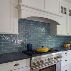 a stove top oven sitting inside of a kitchen next to white cabinets and counter tops