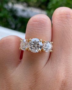 a woman's hand holding a three stone ring with two diamonds on the band