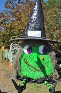 a large green monster with a black hat on it's head sitting in the grass