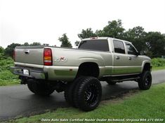 the truck is parked on the side of the road by the grass and trees in the background