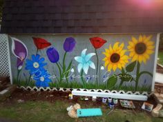 a fence with flowers painted on it in front of a house and some other items