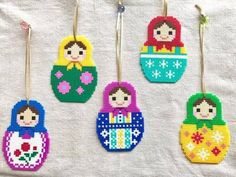 cross stitch russian nesting dolls hanging from clothes pins on a white cloth covered tablecloth