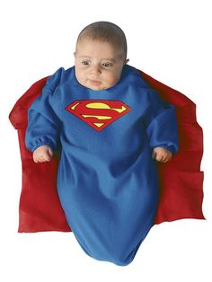 a baby in a superman costume laying on top of a red and blue cloth blanket