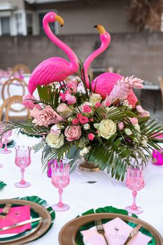 the table is set with flamingos and pink flowers