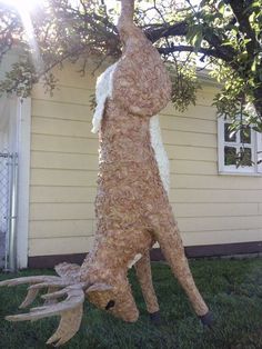 a fake deer that is standing in the grass next to a tree with antlers on it