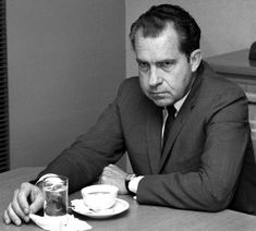 a man sitting at a table with a cup and saucer in front of him