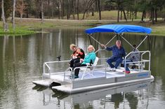 three people are sitting on a pontoon boat in the water with a blue canopy