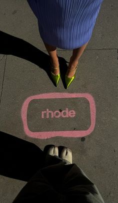 a person standing in front of a sign that reads rhode on the ground next to their feet