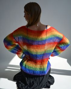 a woman is standing in the sunlight wearing a colorful sweater