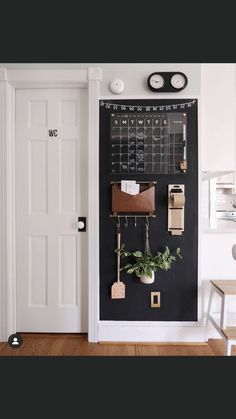 a chalkboard with some plants hanging on it and a clock above the door to the other room