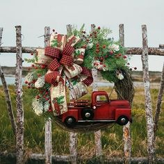 an old red truck with a wreath on it is parked in front of a wooden fence