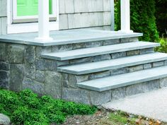 a house with steps leading up to the front door and green doors on each side